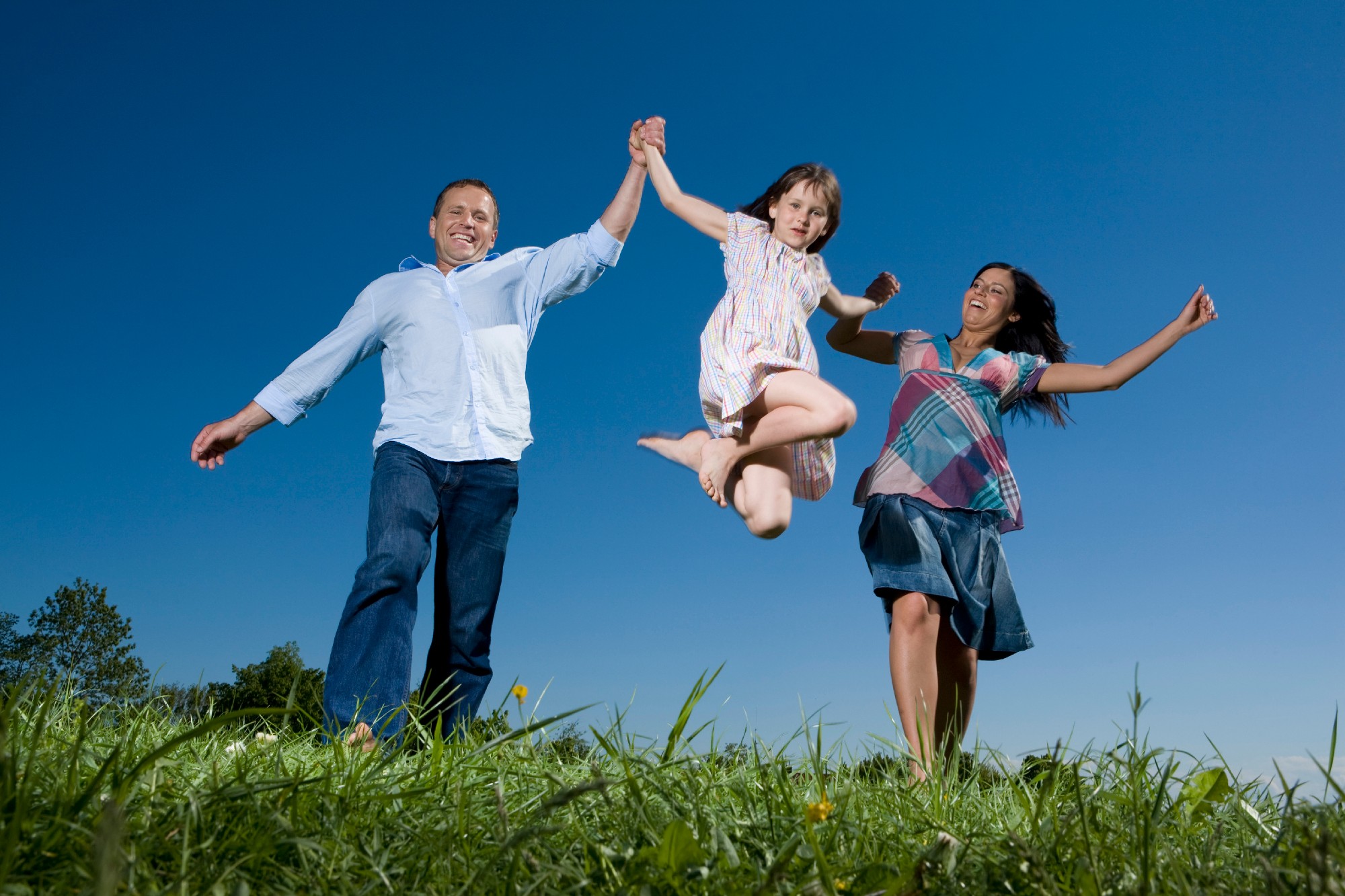 Young Family With Daughter (6 7) Taking A Walk Across Meadow, Having Fun